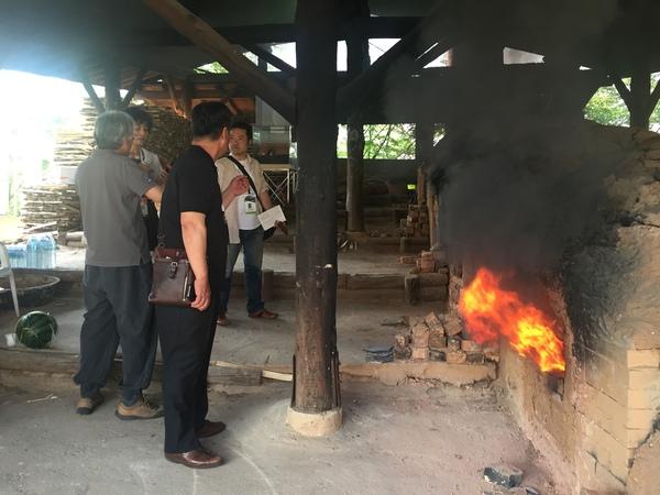 窯から燃え上がる炎の前で、男性と女性4名が話をしている写真