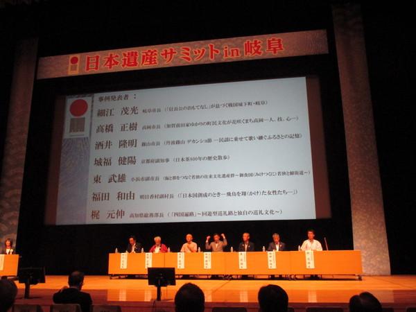 舞台の、プロジェクトスクリーンの横に着席する市長と関係者の写真