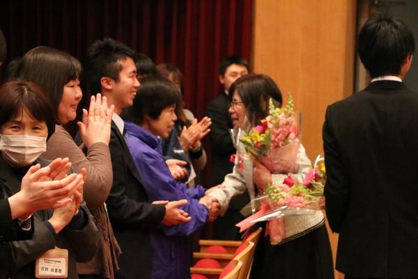 現職員の方に、花束を持った退職者が握手をしている写真