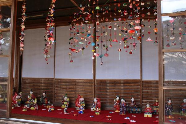 色とりどりのつるし飾りと、床上に並べられた人形の写真