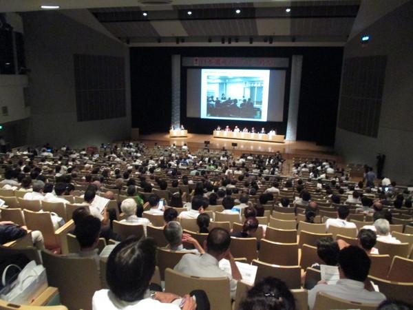 日本遺産サミットに参加した沢山の人が着席し、プロジェクトスクリーンを見ている様子を後方より写した写真