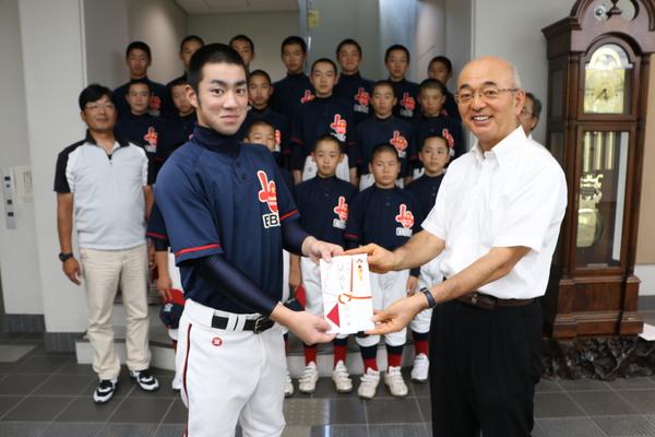 後ろに並ぶ他の選手達が見守る中、キャプテンの安井君がユニフォーム姿で市長と一緒にお祝い袋を持っている写真