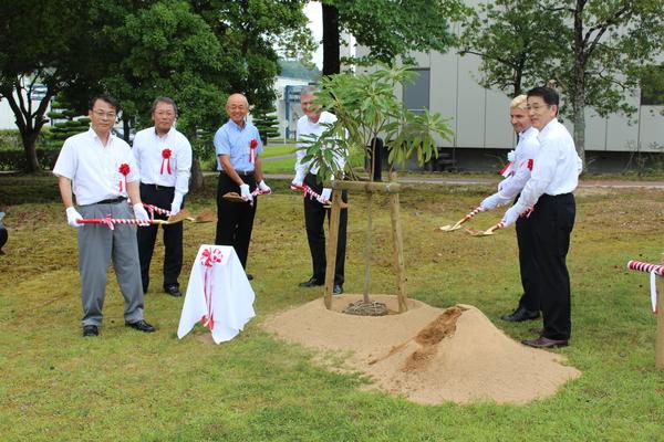 市長やダーク・コッシャ社長さんや関係者の方々が紅白のリボンが巻いてあるスコップを持って、植樹をしている様子の写真