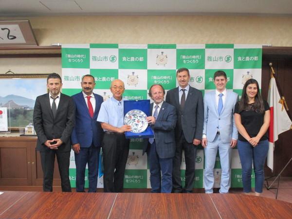 市長と陶芸家の方が二人でお皿を持っていて、その両端に5名の訪問団の方達が並んでいる写真