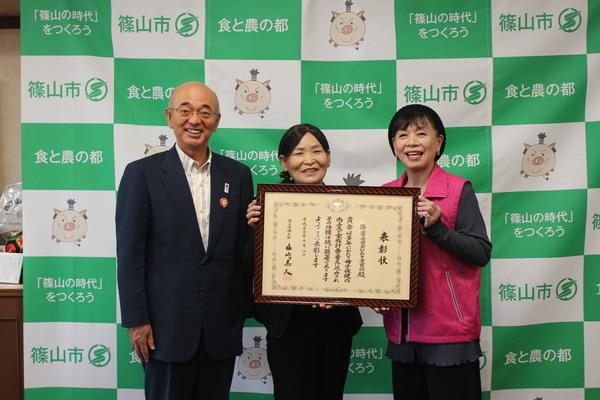 太田 鈴子さんと赤井 紀子さんが2人で額に入った賞状を持ち、市長と笑顔で写っている写真