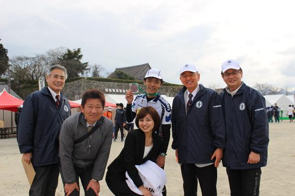 完走した神戸新聞社の安福記者が手作りメダルを首にかけ、アナウンサーの大野聡美さんや川合楊一郎さんと市長・関係者が笑顔で記念撮影写真