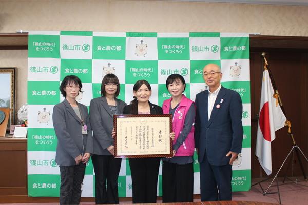 額に入った賞状を2人で持ち、中央に立っている太田 鈴子さんと赤井 紀子さんの隣に市長と関係者の方が笑顔で写っている写真