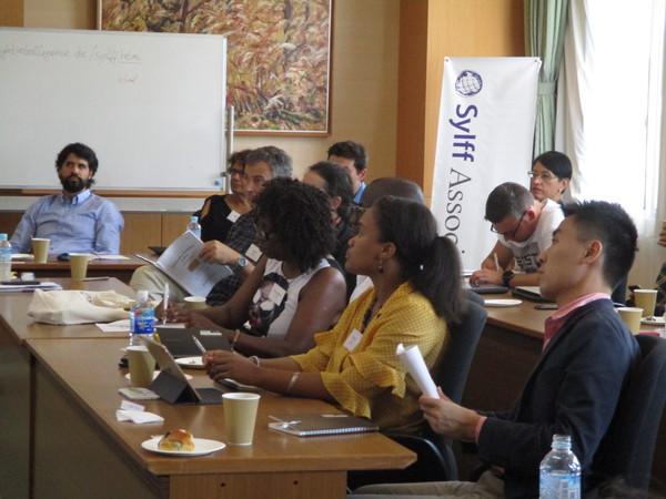 着席し、メモを取ったり、資料を手にし、前方を見ている外国人男女の写真