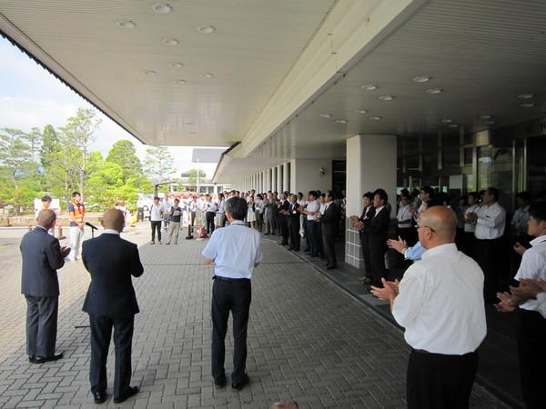 玄関前に沢山の職員が集まり、山本 圭太係長と伊藤 琢郎主事に拍手をしている様子の写真