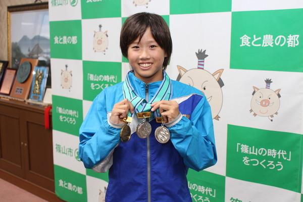 メダル3つをつけて、笑顔で立っている井上 真帆さんの写真