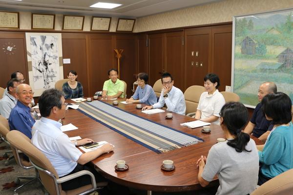 市長室の席に避難者の方々が座り笑顔で話をしていて市長はカメラに向かい笑顔で写っている写真