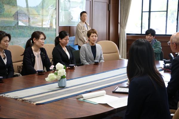 机を囲み座っている中、女性が発言をしている写真