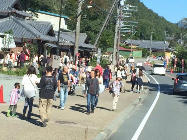 町にはお祭りの宣伝旗がたくさん立っていて、人や車が通っている写真