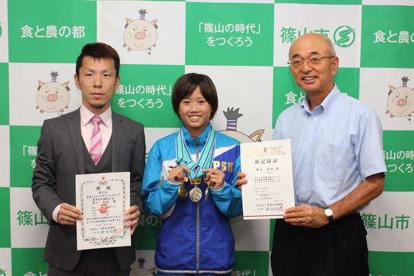 メダル3つをつけて、笑顔の井上 真帆さんと両隣で、賞状と新記録証をもつ市長と、男性の写真