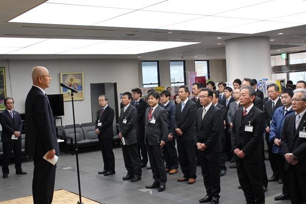 スーツを着た職員が集まり前で市長が挨拶をしている写真