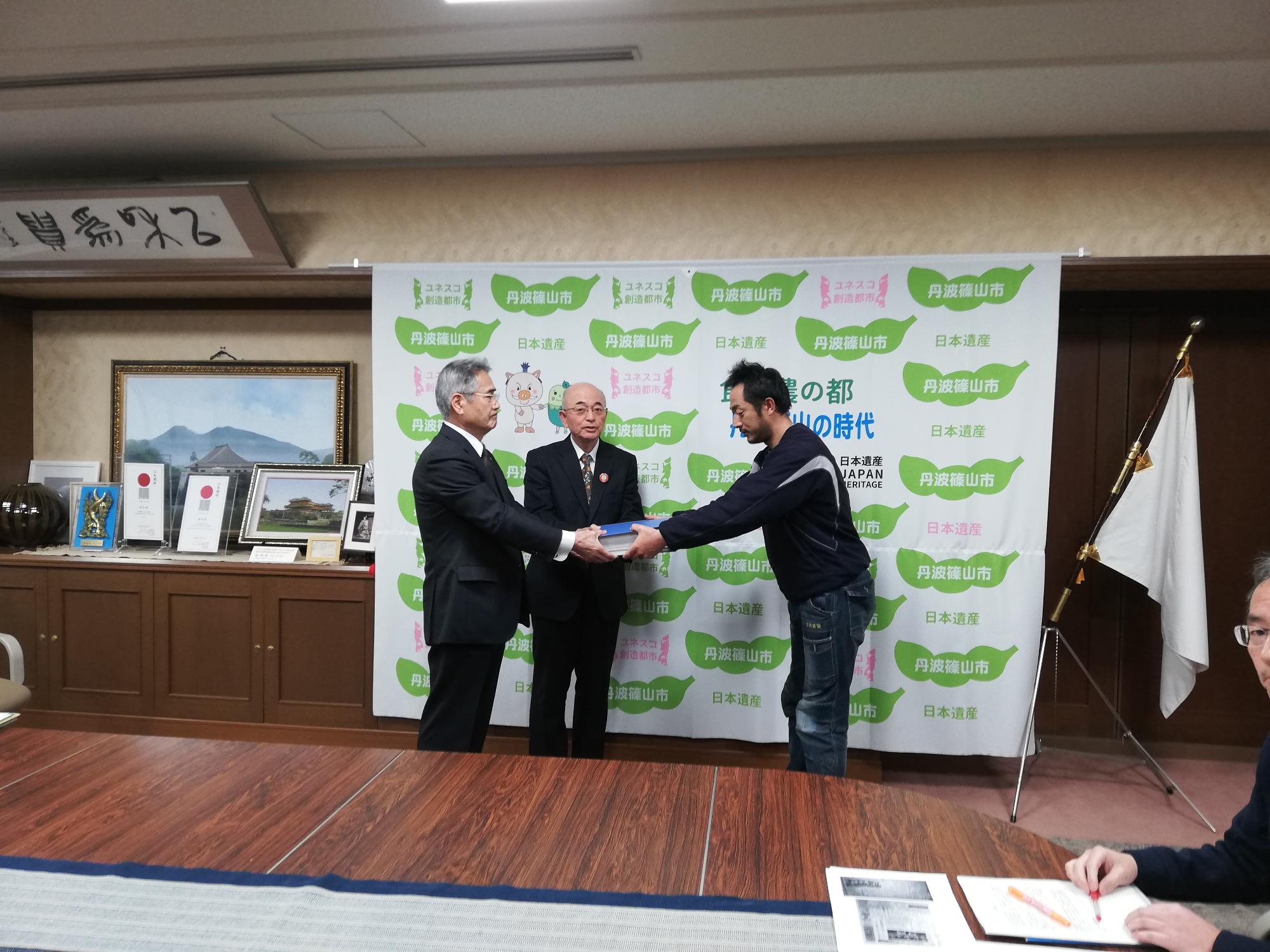 市民の方から前川教育長・酒井市長に署名が手渡されている写真