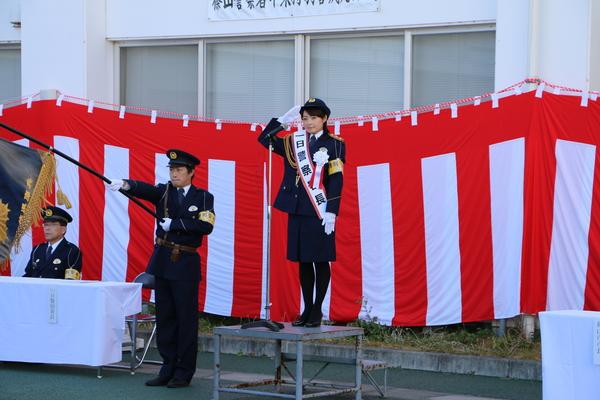 1日警察署長の熊谷 奈美さんが前に立ち、敬礼をしている写真