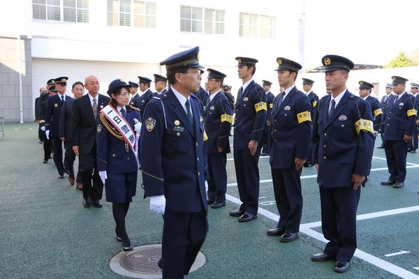 警察官が整列しており、その前を熊谷 奈美さんや市長が歩いている写真