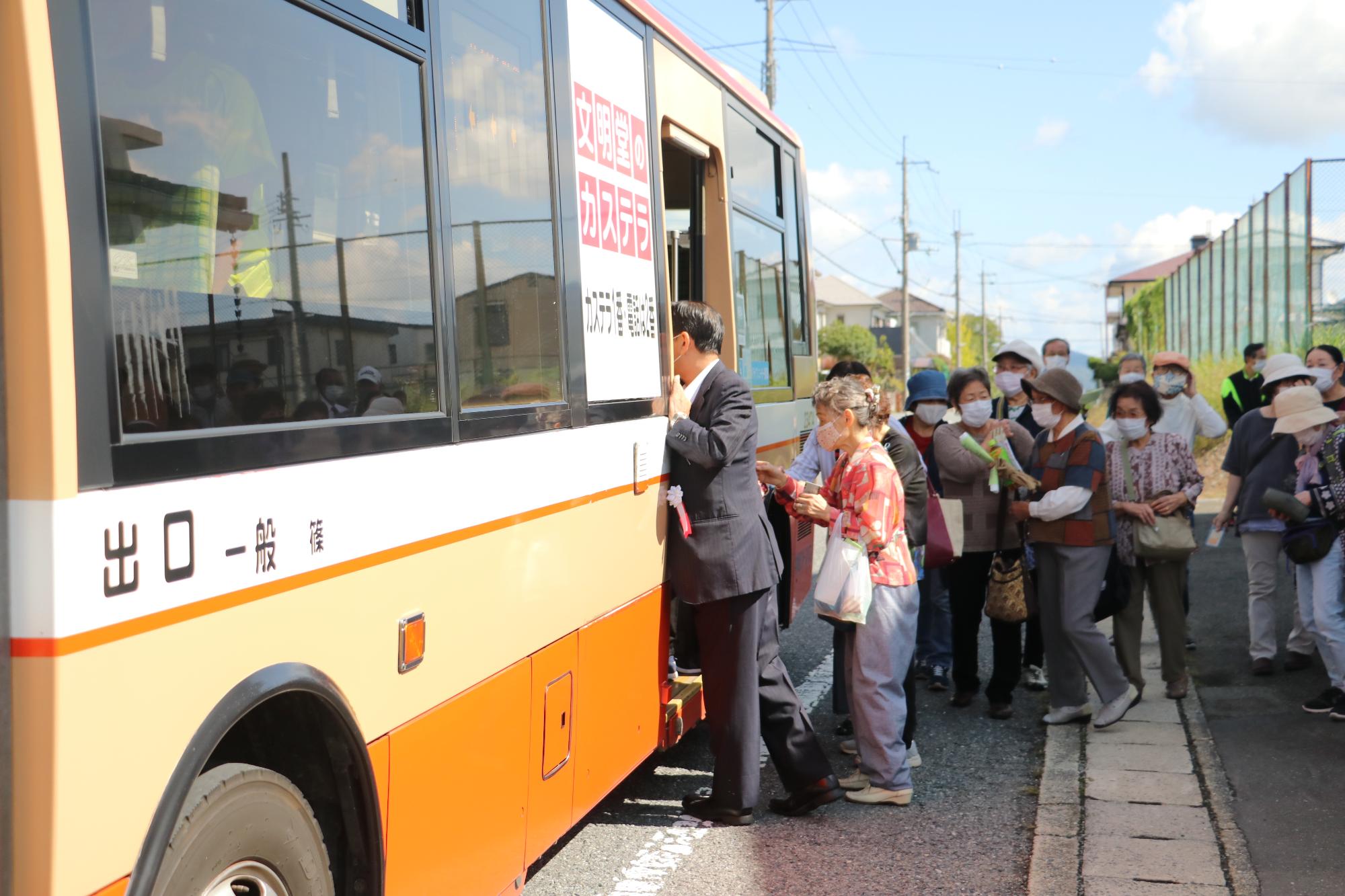 参加者約50名がバスに乗り込もうとしている