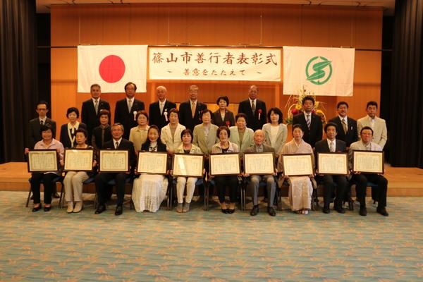 篠山市善行者表彰式で、1列目に額に入った賞状をもつ10人、2列目に立っている11名、3列目に、胸章をつけた6名の写真
