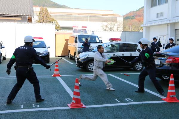 2名の警官が警察棒を持ち、泥棒役の男性を捕まえようとしている写真