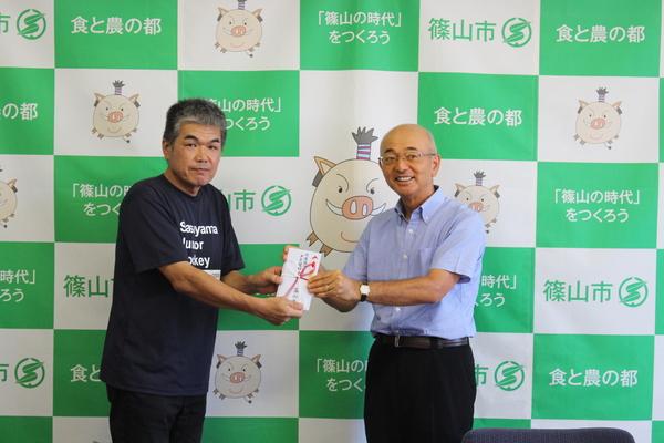 篠山ジュニアホッケークラブ会長の岩木さんと市長で祝い金を持ち記念写真