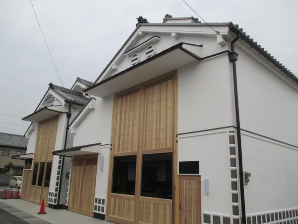 白い壁と、うすい木目調の扉のある、落ち着いた色合いの山倉2棟の写真