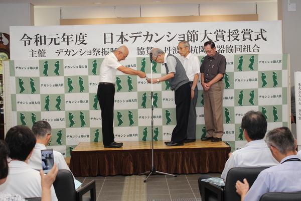 市長から記念品を受け取る優秀賞の村岡さん、その横に並ぶ、相原さん、前田さんの写真