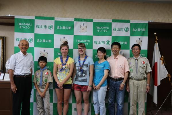 篠山市と書かれた壁の前でベルギーの女性2人や市長たちが並んでいる写真