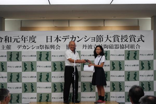 こども・若者賞の貝原さんが、市長から記念品を受け取る写真