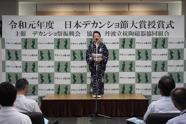 舞台上で、着物を着てマイクの前に立つ大賞の前川さんの写真