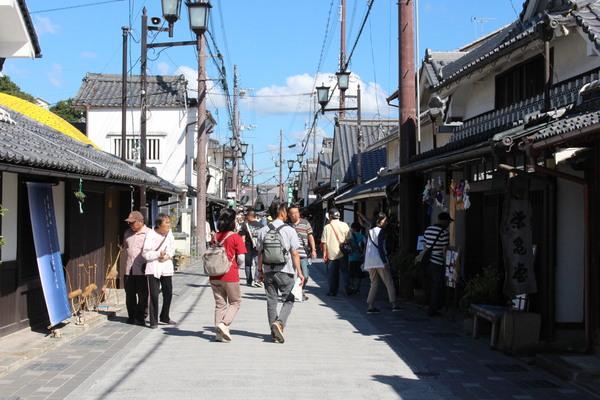 青空の下、沢山の人たちが古いまちなみを歩いている写真