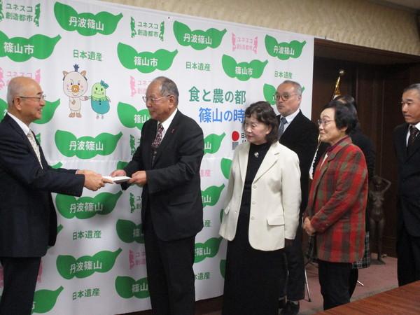 篠山市自治基本条例検証委員会の平野様が答申を市長に手渡ししている様子の写真