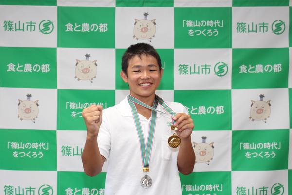白いポロシャツに金と銀のメダルを首にかけている松葉君が、右手はガッツポーズをして、左手に金メダルを持って写っている写真