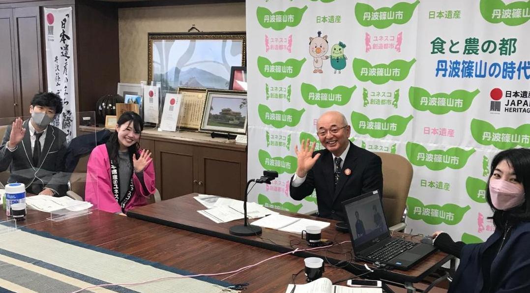 市長や職員が椅子に座って手を振っている