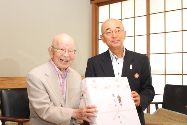 101歳の波部 時雄さんが市長より記念品を受け取っている写真