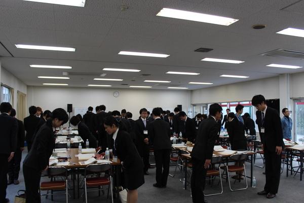 スーツを着た男女が近くの人と向かい合い、お辞儀をしている写真