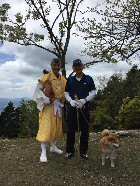 山中で犬を連れた市長と、修行僧の様な着物を着てホラ貝を持った恒田さんが並んでいる写真