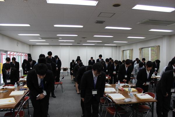 スーツを着た男女が、前を向いて頭を下げている写真