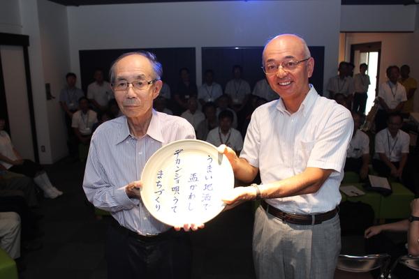 大賞の西尾さんと市長が、デカンショ節「うまい地酒で盃かわしデカンショ唄うてまちづくり」が書かれたプレートを一緒に持っている写真