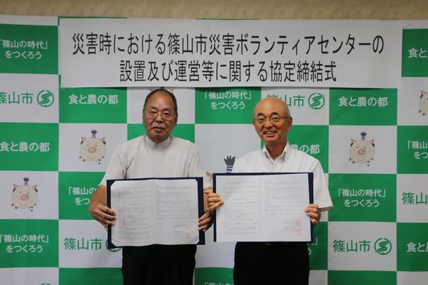 社会福祉協議会長の平野 芳行さんと市長が災害ボランティアセンターの協定書を持っている写真