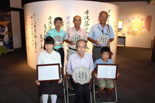 受賞者が、それぞれプレートや、額に入った賞状を持っている写真