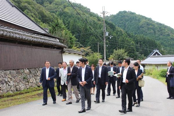 梶山 弘志大臣に緑の山々の集落丸山の案内をしている関係者の人達の写真