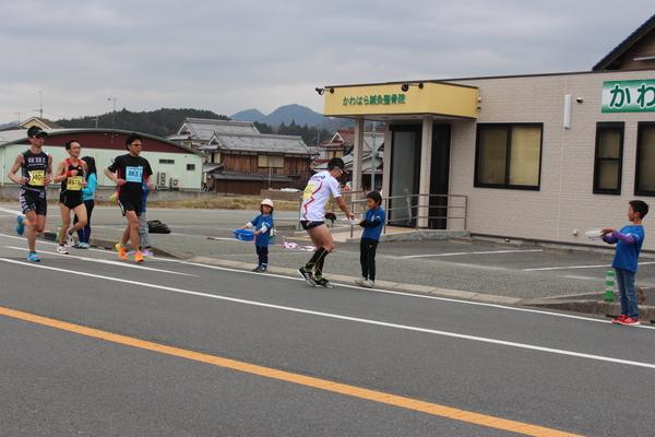 ランナーが、差し入れをする子供達から受け取っている写真