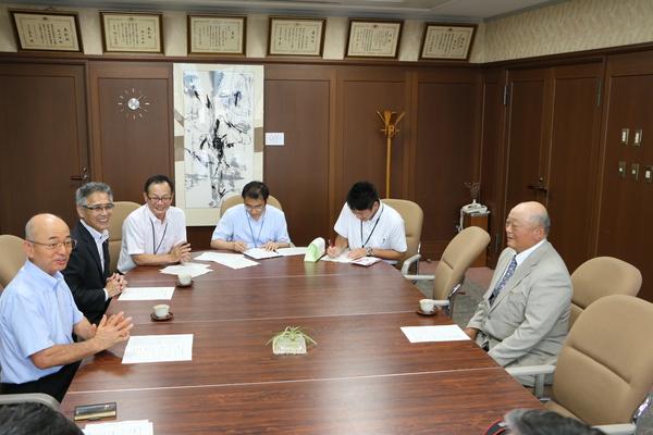 市長と井関 道夫さんと関係者が座り、話をしている写真