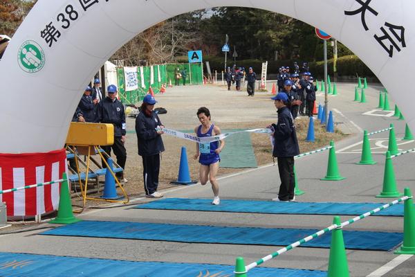 ブルーユニフォームを着たランナーがゴールテープを切る瞬間の写真