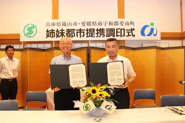 調印式の書類を手に持ち市長と男性が記念写真