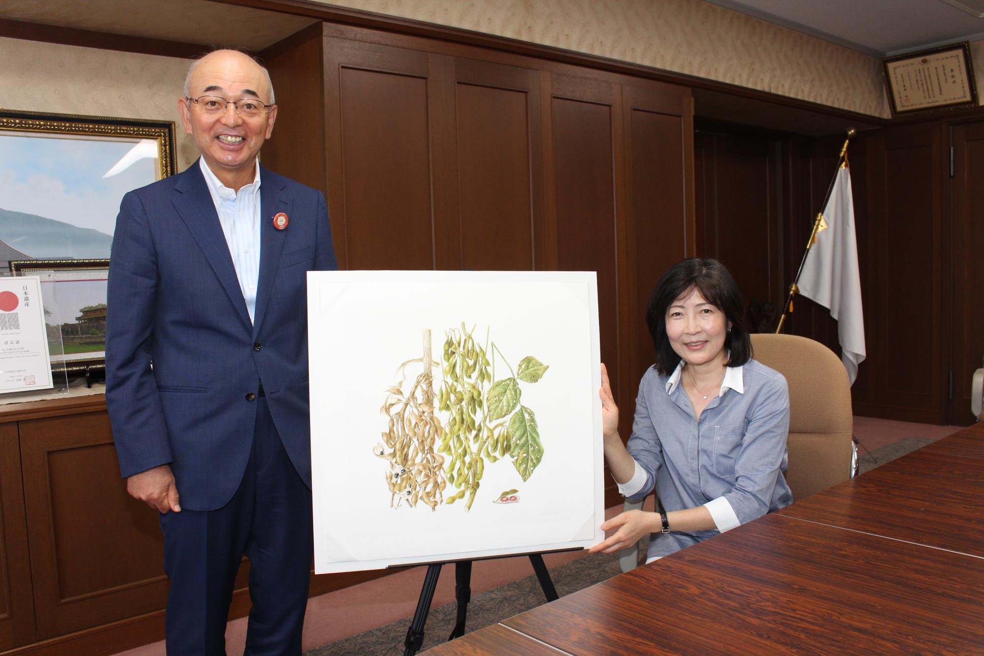 市長と榎戸さんが黒豆と枝豆の絵画をはさんで記念撮影