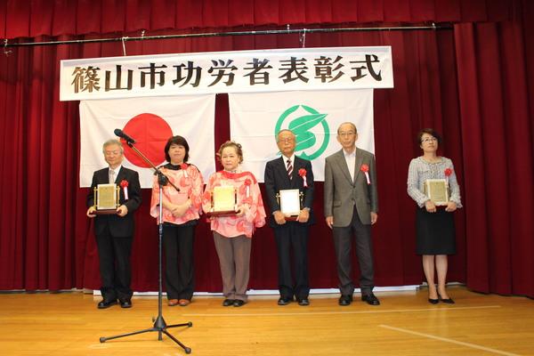 壇上で受賞者男性3名、女性3名が賞状の入った盾を持っている写真