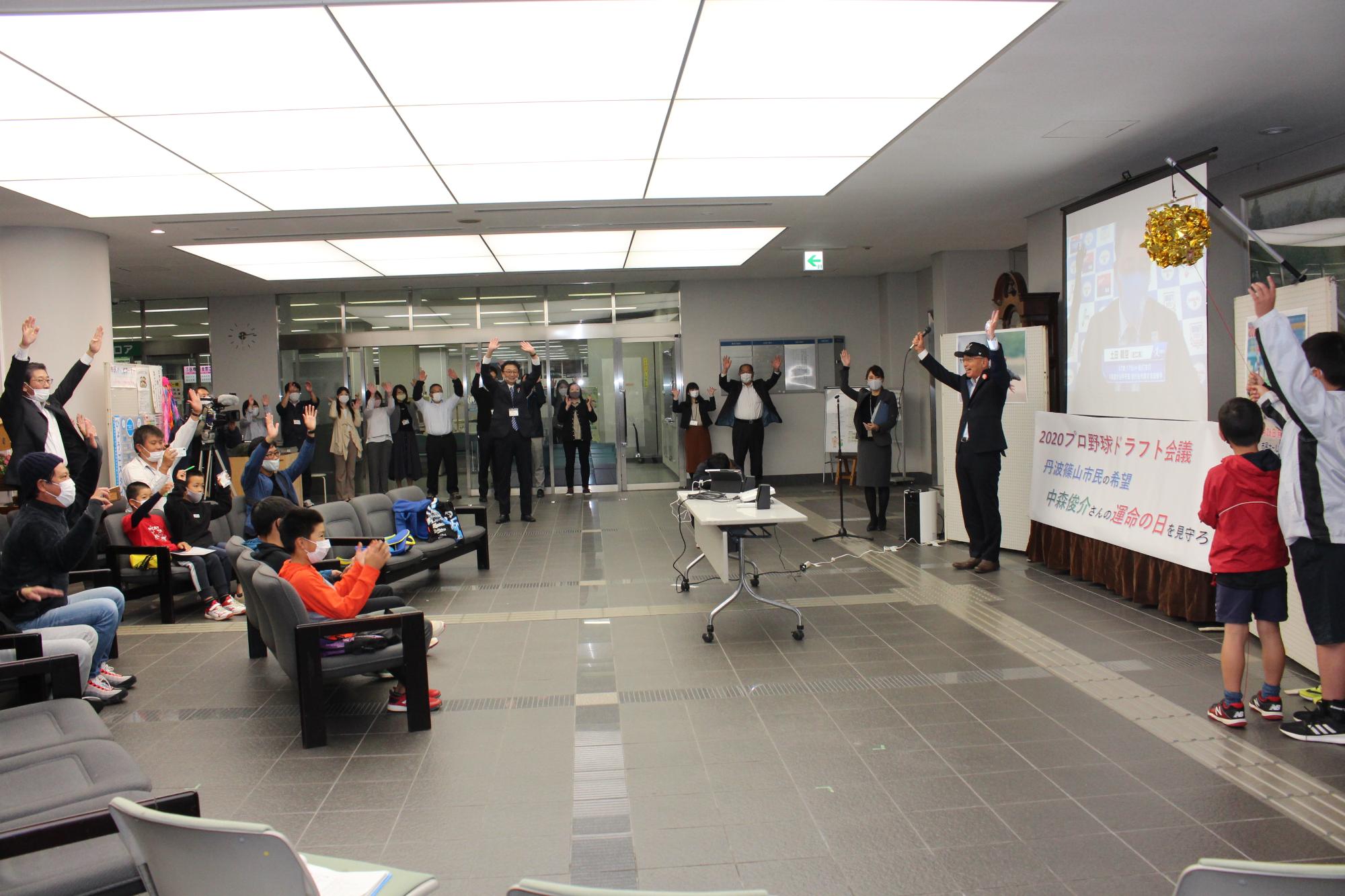 市民ホール駆け付けた参加者が万歳をしている